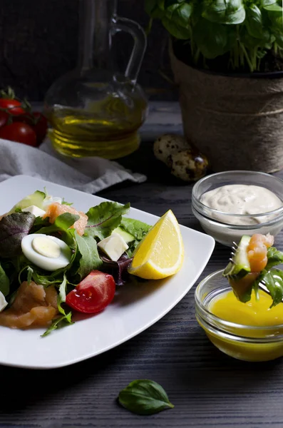 Beyaz tabak üzerine odaklanmış salata, somon ve sebzeler koyu ahşap masa üzerinde, dikey görüntü yakın