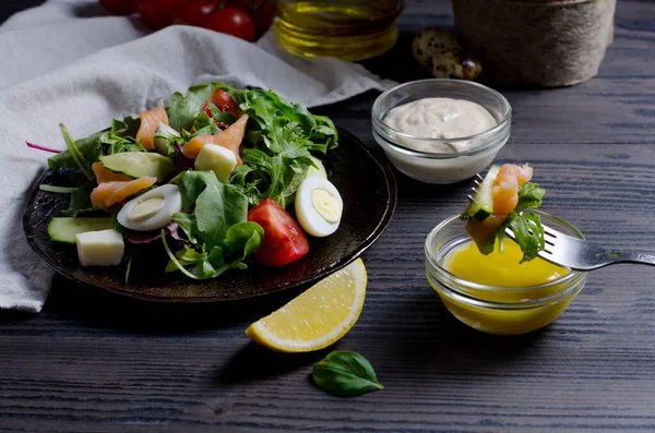 Somon ve sebze salatası koyu tabakta, yakın plan koyu ahşap masada.