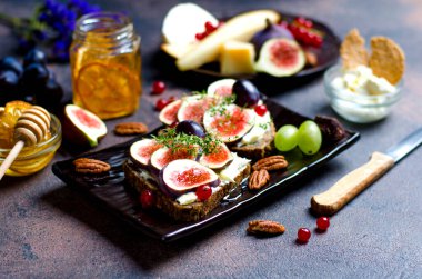 Mascarpone ve incir meyveli aperatif, ön planda bal, üzüm, peynir ve fındık.
