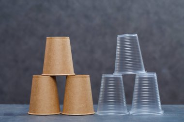 Gri arka planda bambu ahşap ve kağıttan yapılmış çevre dostu tek kullanımlık sofra takımı. Plastik tabak ve çatal bıçak takımı. Çevreye önem vermek. Geri dönüşüm sorunu. Güvenli gezegen, çevre kavramı.