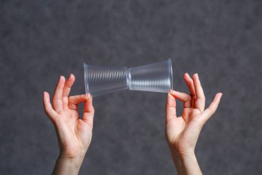 Plastik, şeffaf, tek kullanımlık bardaklar kadınların elinde.