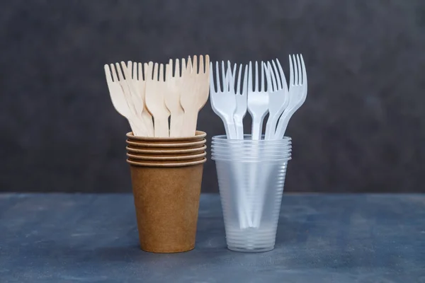 Eco-friendly disposable tableware made of bamboo wood and paper on a gray background. Plastic dishes and cutlery. Caring for the environment. Recycling problem. safe planet, environmental concept.