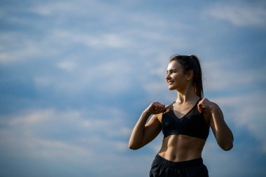 Sağlıklı yaşam tarzı kavramı. Spor giyim sektöründe genç ve çekici bir kadın şafak vakti doğayla ilgilenmeden önce elini uzatıyor. Kas ısınması