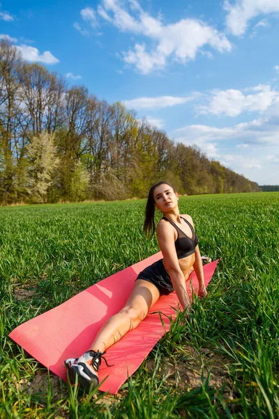 Young athletic woman doing longitudinal splits outdoors. Girl go in for sports, healthy lifestyle, athletic body. She is in sportswear, black top and shorts. Sport concept.