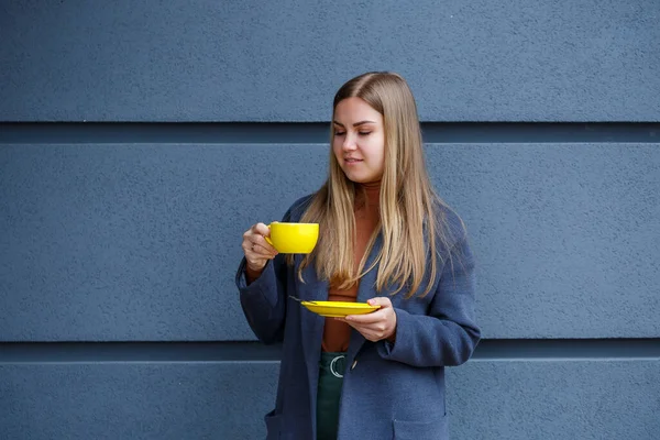 Ung Smuk Blond Kvinde Grå Frakke Drikker Varm Fra Gul - Stock-foto