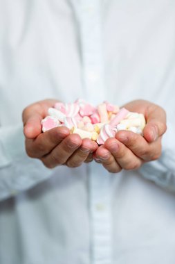 Bir adam ellerindeki şekerlemeleri yiyor. Parlak adam portresi. Tatlılar bir adamın ellerinde. Şekerli neşeli adam portresi