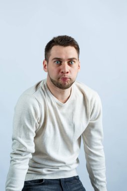 Beyaz arka planda beyaz kazaklı genç bir adam. Sıradan giyinmiş şık bir adam. Her gün için erkek görüntüsü