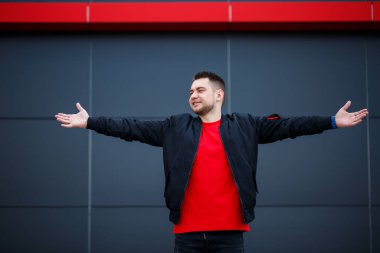 Gri bir arka planda duran şık bir adamın tam boy portresi. Reklam mesajınız için yer var. Ceket ve yüzünde gülümseme olan tişört giyen yakışıklı bir adam.