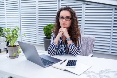 Dizüstü bilgisayarda çalışan güzel genç bir kadın ve dışarıda bir kafede otururken gülümsüyor. Genç bir kadın iş için laptop kullanıyor. Açık bir kafede dizüstü bilgisayarda çalışan serbest çalışan bir kadın..