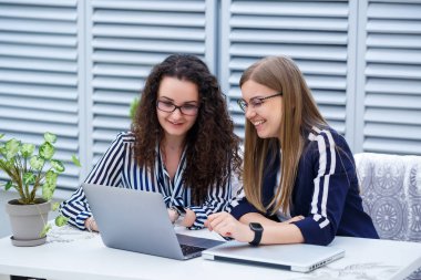 İki iş kadını parlak bir kafede dizüstü bilgisayarları ve iş belgeleriyle oturup ciddi insanlarla konuşuyorlar. Ofis çalışanları kahve molalarında oturuyorlar ve çalışıyorlar. Bir kafede iş görüşmesi.