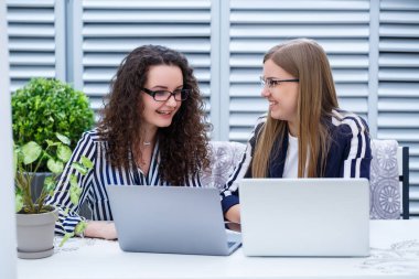 İki iş kadını parlak bir kafede dizüstü bilgisayarları ve iş belgeleriyle oturup ciddi insanlarla konuşuyorlar. Ofis çalışanları kahve molalarında oturuyorlar ve çalışıyorlar. Bir kafede iş görüşmesi.