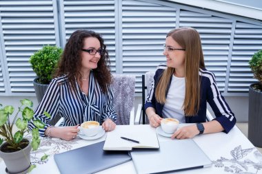 Gülümseyen başarılı kadın işçiler birlikte çalışıyor, terasta dizüstü bilgisayar üzerinde çalışıyorlar, bayan meslektaşlar fikirleri tartışmakla meşguller, iş toplantısındaki kızlar. İş konsepti