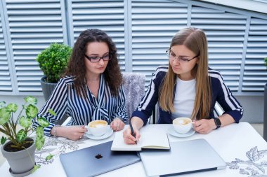 Gülümseyen başarılı kadın işçiler birlikte çalışıyor, terasta dizüstü bilgisayar üzerinde çalışıyorlar, bayan meslektaşlar fikirleri tartışmakla meşguller, iş toplantısındaki kızlar. İş konsepti