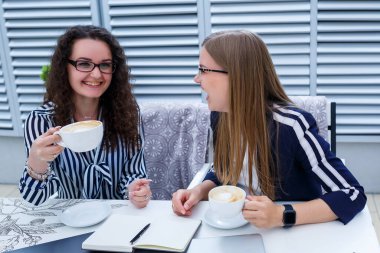 Gülümseyen başarılı kadın işçiler birlikte çalışıyor, terasta dizüstü bilgisayar üzerinde çalışıyorlar, bayan meslektaşlar fikirleri tartışmakla meşguller, iş toplantısındaki kızlar. İş konsepti