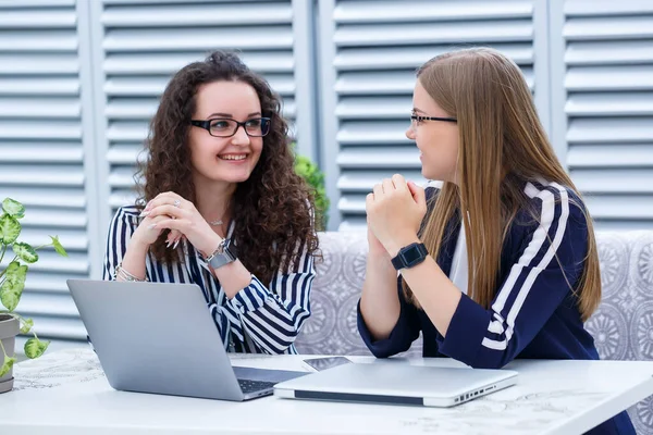 İki iş kadını parlak bir kafede dizüstü bilgisayarları ve iş belgeleriyle oturup ciddi insanlarla konuşuyorlar. Ofis çalışanları kahve molalarında oturuyorlar ve çalışıyorlar. Bir kafede iş görüşmesi.
