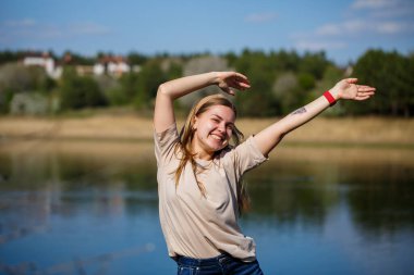 Göl kenarında dans eden bir kız, güneşli bir hava. Genç bir kadın hayattan zevk alır, dans eder ve şarkı söyler. Keyfi yerinde ve yüzünde bir gülümseme var..