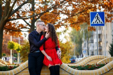 Siyah tişörtlü bir adam ve sonbahar caddesinde kırmızı elbiseli bir kız.