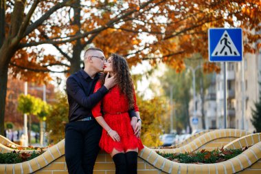 Siyah tişörtlü bir adam ve sonbahar caddesinde kırmızı elbiseli bir kız.