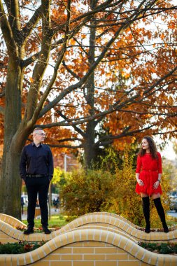 Siyah tişörtlü bir adam ve sonbahar caddesinde kırmızı elbiseli bir kız.