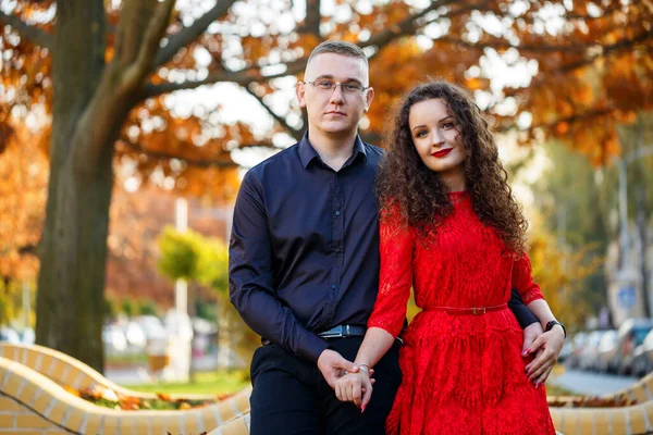 Siyah tişörtlü bir adam ve sonbahar caddesinde kırmızı elbiseli bir kız.