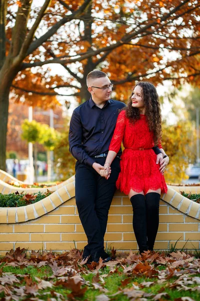 Siyah tişörtlü bir adam ve sonbahar caddesinde kırmızı elbiseli bir kız.