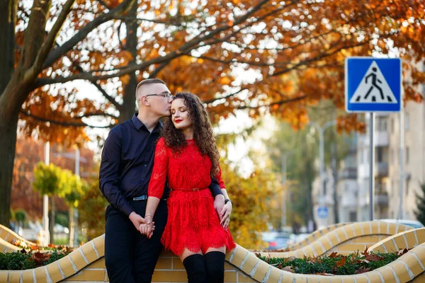 Siyah tişörtlü bir adam ve sonbahar caddesinde kırmızı elbiseli bir kız.