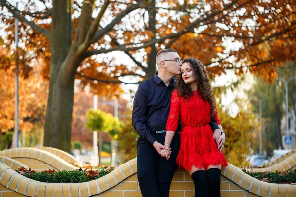 Siyah tişörtlü bir adam ve sonbahar caddesinde kırmızı elbiseli bir kız.