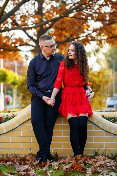 Siyah tişörtlü bir adam ve sonbahar caddesinde kırmızı elbiseli bir kız.