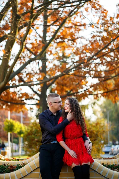 Siyah tişörtlü bir adam ve sonbahar caddesinde kırmızı elbiseli bir kız.