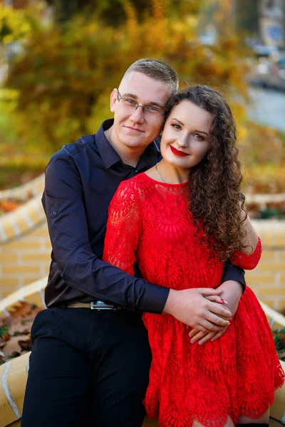 Siyah tişörtlü bir adam ve sonbahar caddesinde kırmızı elbiseli bir kız.