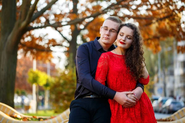 Siyah tişörtlü bir adam ve sonbahar caddesinde kırmızı elbiseli bir kız.