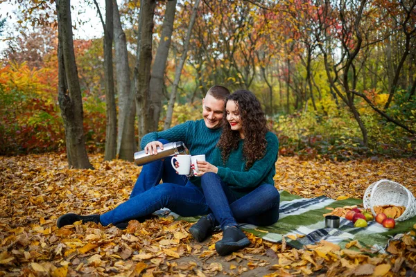 穿着毛衣的情侣们在秋天的森林里喝茶 — 图库照片