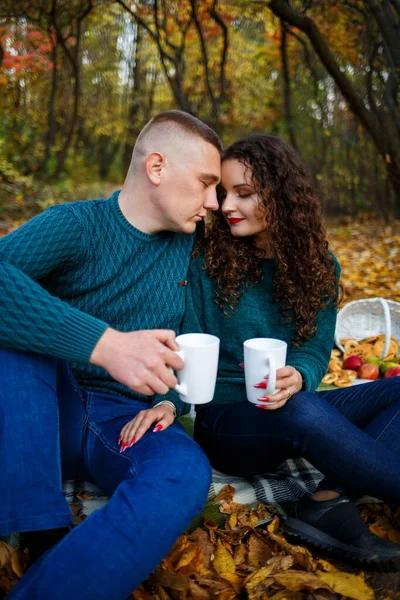 Kazaklı bir çift sonbahar ormanında çay içer.