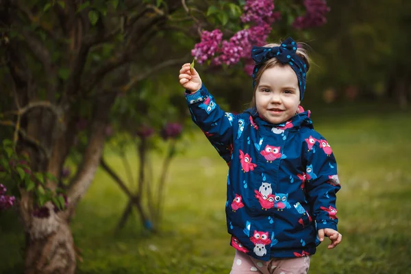 Küçük Bir Kız Leylak Çalılarının Yanında Duruyor Gülümsüyor Mor Çiçekleri — Stok fotoğraf