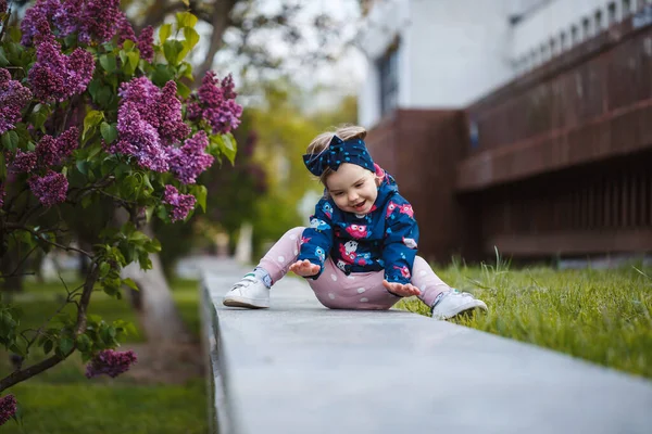 Little Girl Stands Lush Bush Lilacs She Smiles Sniffs Purple — Stock Photo, Image