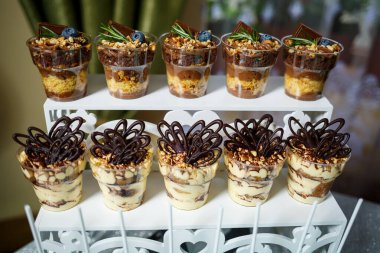 Pastaların, keklerin, şekerlemelerin, cevizlerin olduğu güzel dekore edilmiş bir açık büfe masası. Parti için tatlı masası, düğün için hediyeler. Kapatın. Çikolata. Düğün için açık büfe.