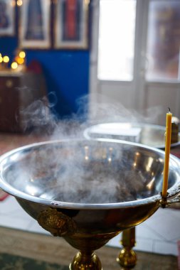 Bebeği kilisede yıkamak için yazı tipine su dökülüyor, dini gelenekler.