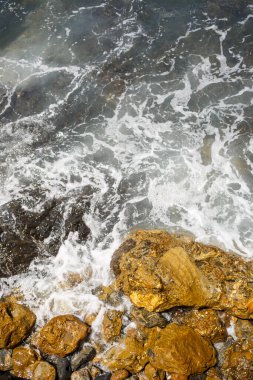 Mavi Akdeniz 'in harika manzarası. Güneşli kayalar, köpüklü dalgalar ve su sıçraması. Dalga kıyıdaki kayalara çarpar.