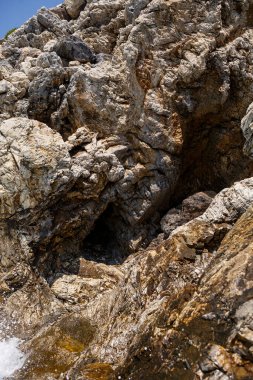Mavi Akdeniz 'in harika manzarası. Güneşli kayalar, köpüklü dalgalar ve su sıçraması. Dalga kıyıdaki kayalara çarpar.