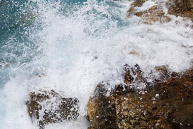 Mavi Akdeniz 'in harika manzarası. Güneşli kayalar, köpüklü dalgalar ve su sıçraması. Dalga kıyıdaki kayalara çarpar.