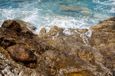 Mavi Akdeniz 'in harika manzarası. Güneşli kayalar, köpüklü dalgalar ve su sıçraması. Dalga kıyıdaki kayalara çarpar.