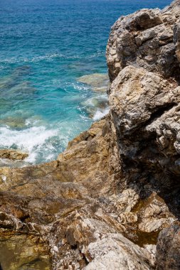 Mavi Akdeniz 'in harika manzarası. Güneşli kayalar, köpüklü dalgalar ve su sıçraması. Dalga kıyıdaki kayalara çarpar.