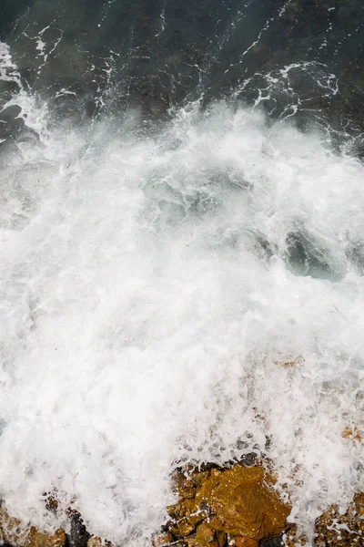 Mavi Akdeniz 'in harika manzarası. Güneşli kayalar, köpüklü dalgalar ve su sıçraması. Dalga kıyıdaki kayalara çarpar.