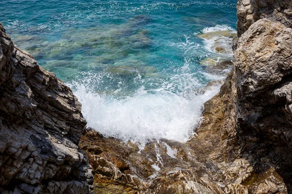 Mavi Akdeniz 'in harika manzarası. Güneşli kayalar, köpüklü dalgalar ve su sıçraması. Dalga kıyıdaki kayalara çarpar.