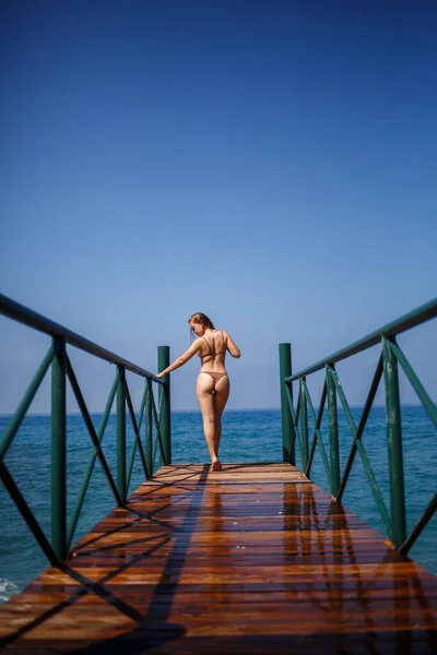 夏日阳光明媚 身穿棕色泳衣的年轻漂亮女子在海滨的码头上散步 — 图库照片