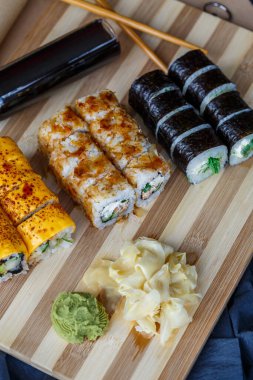 Suşi seti farklı türde rulo ve yılan balığı, somon, ton balığı, karides, kırmızı havyar ve tobiko uçan balık yumurtasından yapılmış sashimi. Pan-Asya ve Asya yemekleri ve tabaklar siyah beton mutfak masasında.