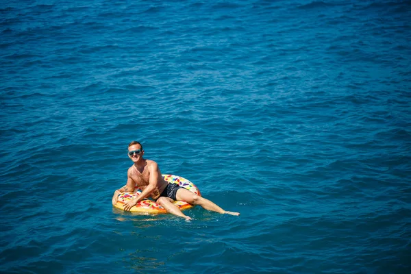 Młody Człowiek Unosi Się Nadmuchiwanym Pierścieniu Powietrznym Morzu Niebieską Wodą — Zdjęcie stockowe