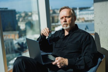 Çarpıcı şehir görüşüne sahip bir ofiste, odaklanmış bir birey, verimli bir gün için verimliliği ve refahı artırmak için dizüstü bilgisayar işini ve rahatlama tekniklerini ustalıkla dengeler.