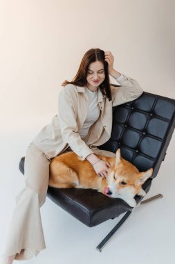 Corgi köpeğiyle oynayan genç bir kadın. Sağlıklı bir yaşam tarzı ve evcil bir hayvanla bir dairede yaşamak. Evcil hayvan konsepti.
