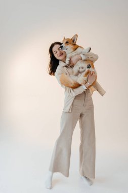 Corgi köpeğiyle oynayan genç bir kadın. Sağlıklı bir yaşam tarzı ve evcil bir hayvanla bir dairede yaşamak. Evcil hayvan konsepti.